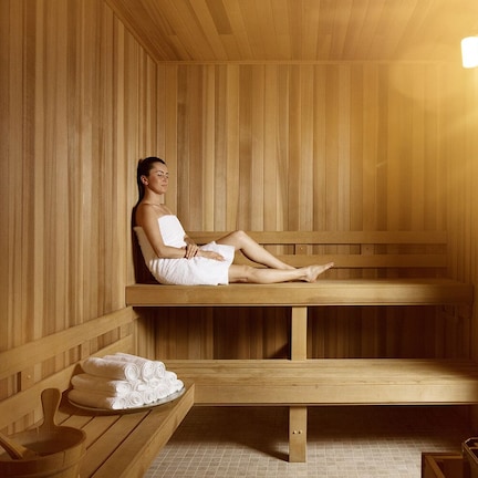 A wooden sauna with benches, a towel rack, and a bench with towels.