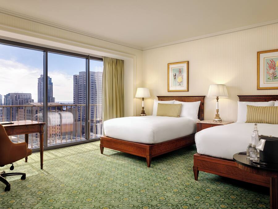 A hotel room with two beds, a desk, and a chair.