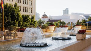 A fountain with multiple water jets in a courtyard with seating and potted plants. - Westgate Hotel (San Diego)