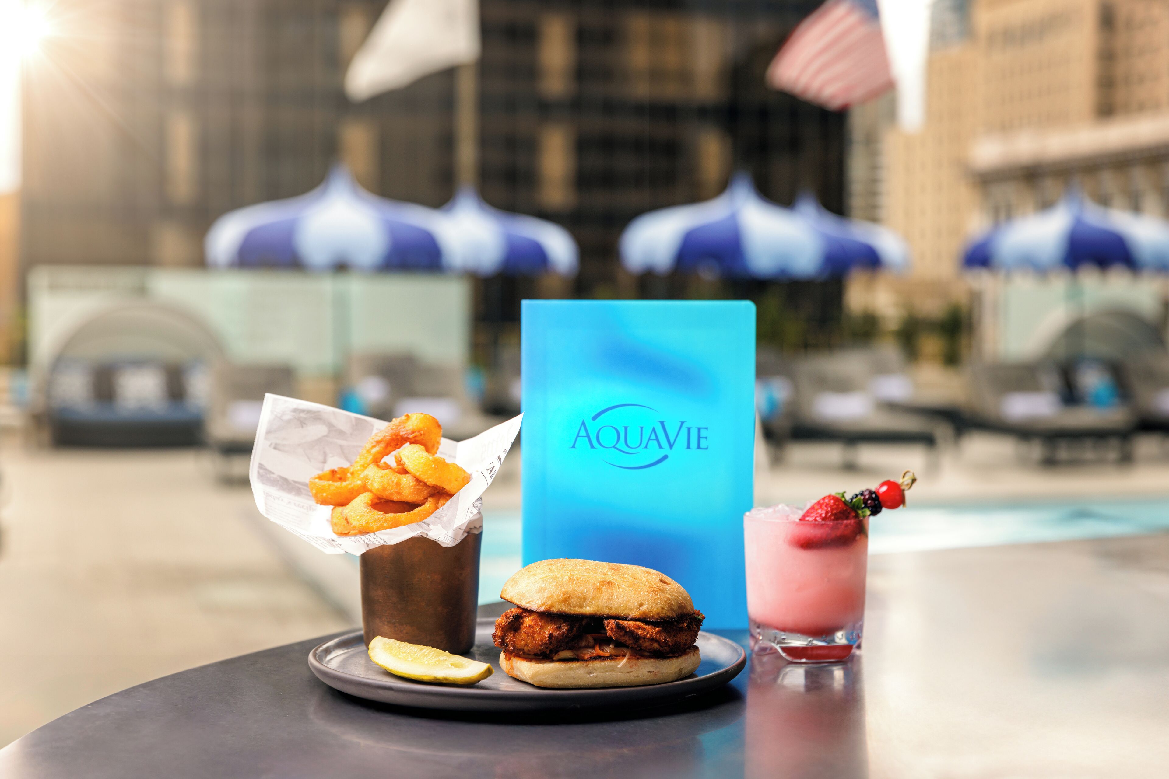 A dining table with a sandwich, fries, a drink, and a blue menu.