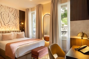 Una camera d'albergo con un letto, una scrivania con un telefono e vista sull'esterno dalle finestre.