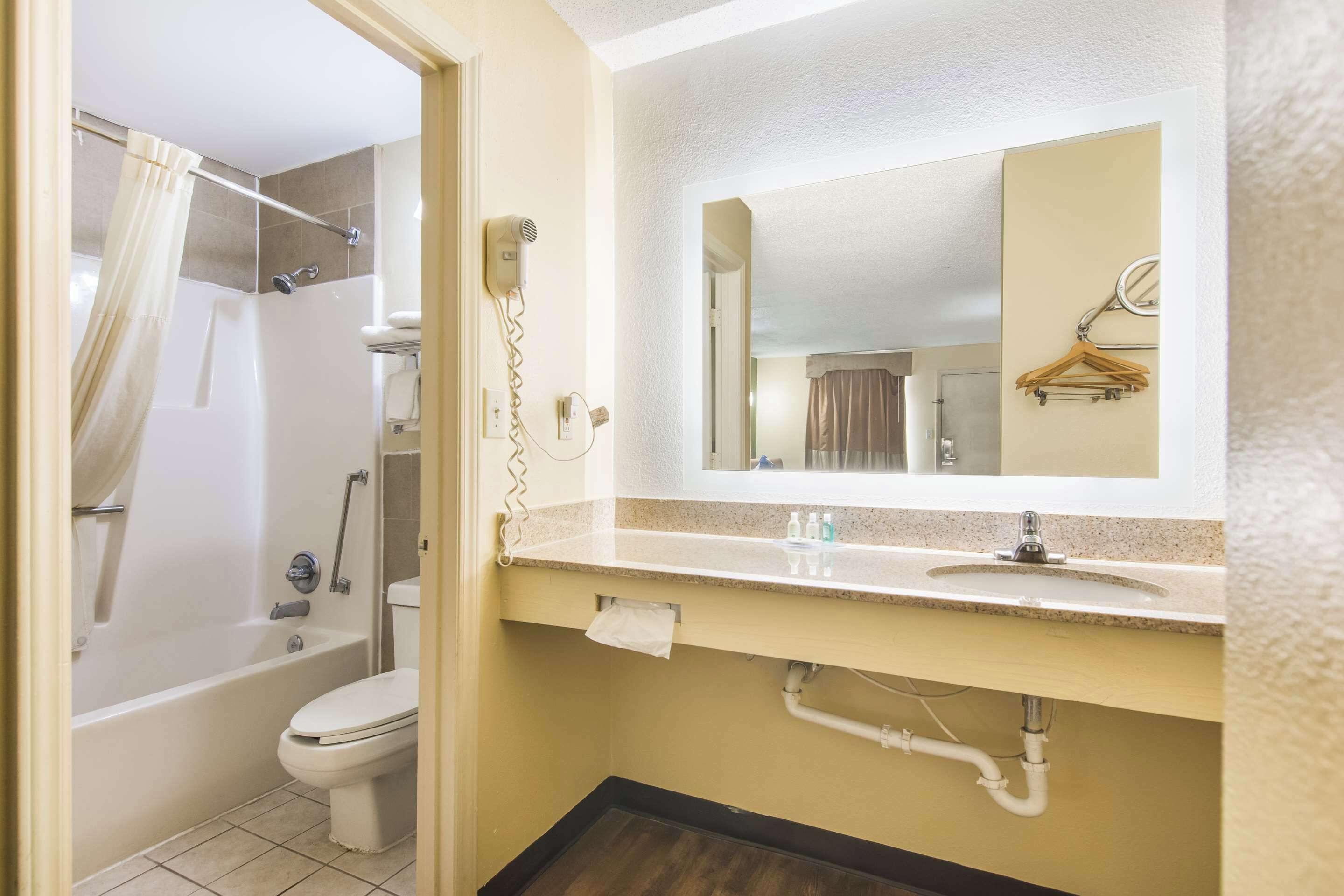 A bathroom with a bathtub, toilet, sink, and a mirror above the sink.