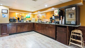 Une cuisine avec des meubles de rangement en bois, un réfrigérateur, un four à micro-ondes et une machine à café.