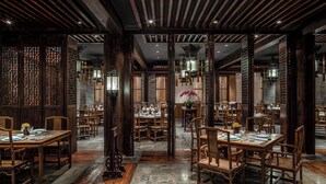 Un comedor tradicional con mesas y sillas de madera, una lámpara central y faroles decorativos.