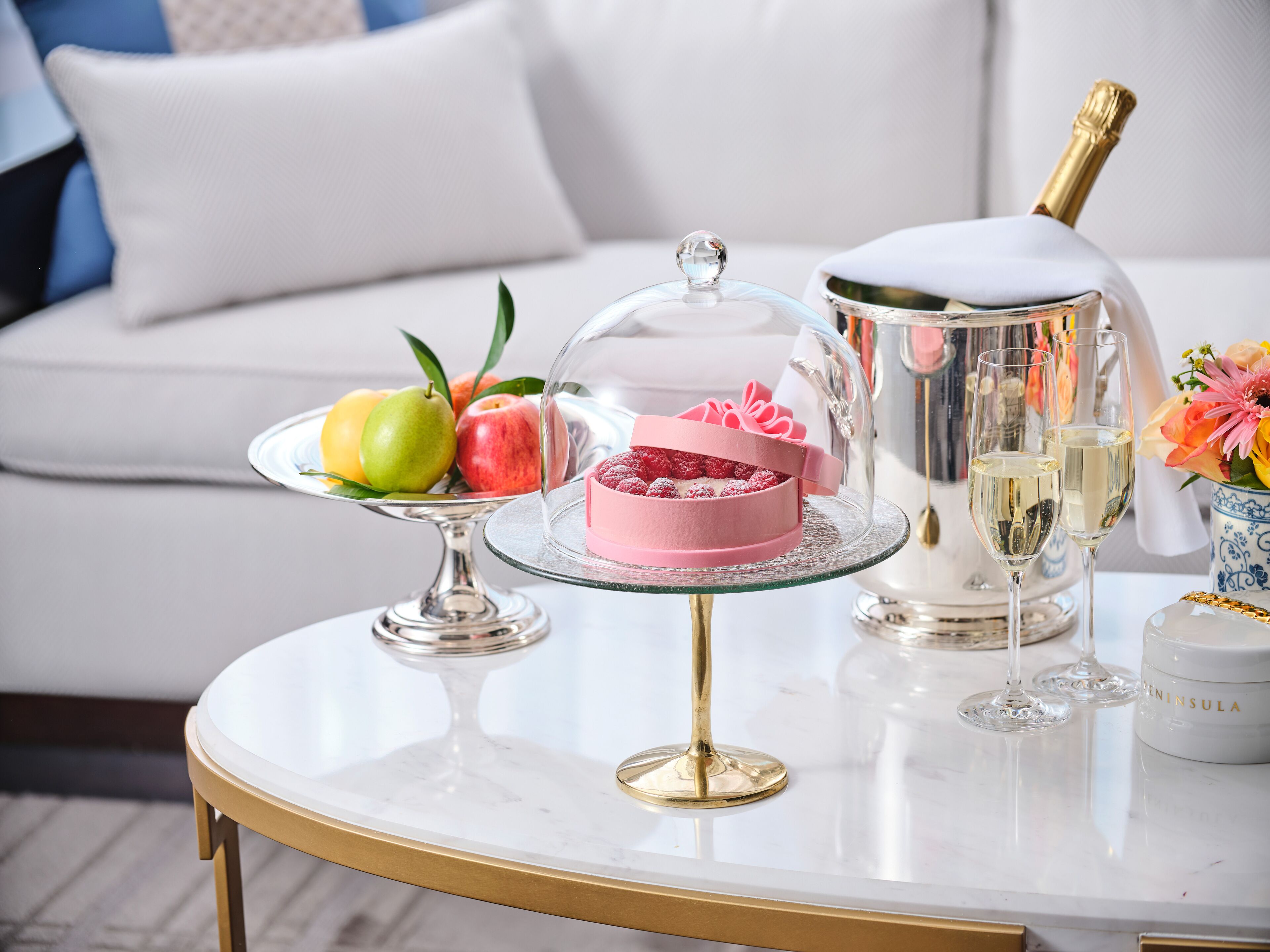A table with a cake, champagne, and fruits.