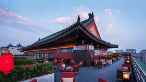 Un restaurante en la azotea con arquitectura china tradicional, mesas al aire libre y faroles rojos.