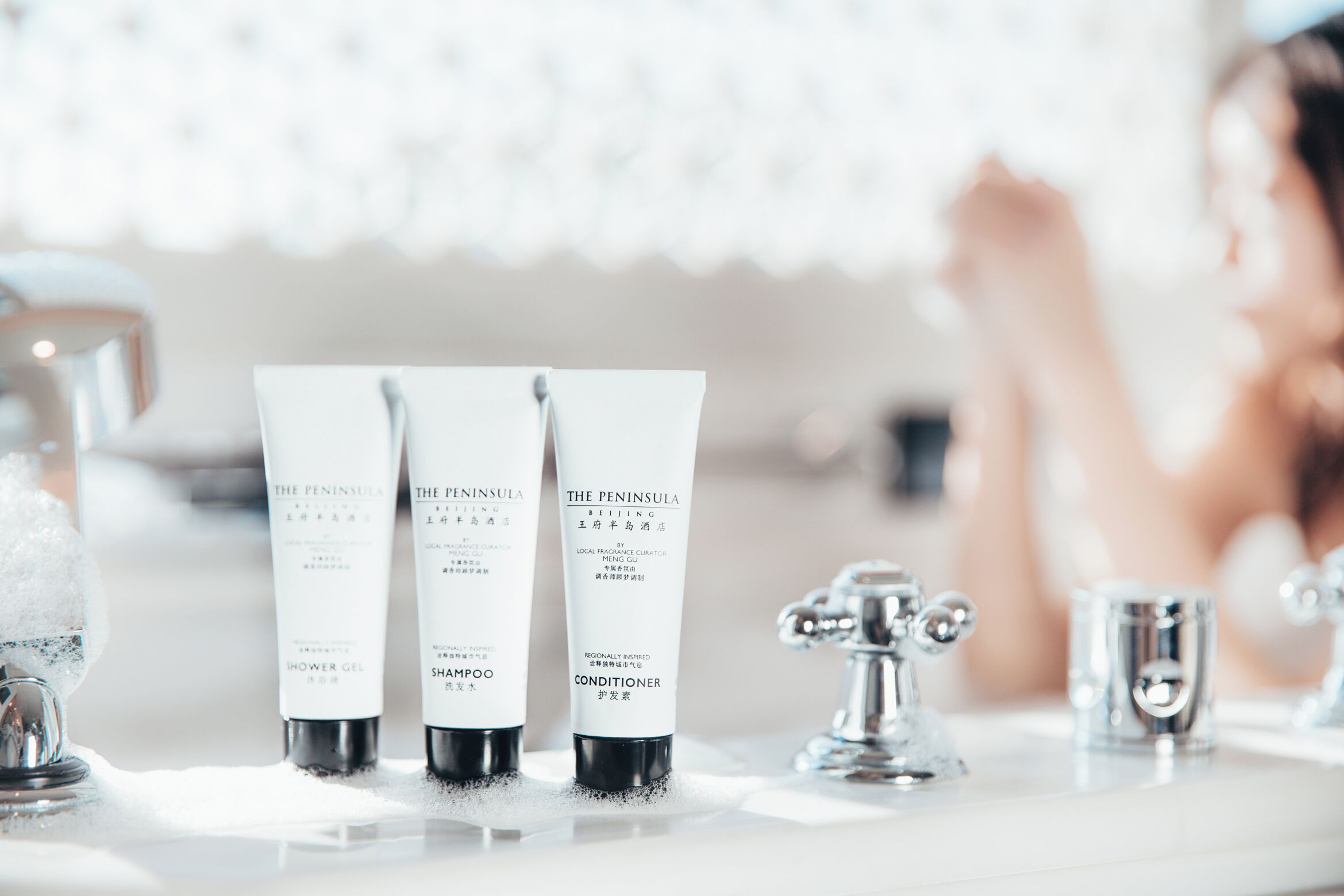 Three bottles of The Peninsula skincare products on a bathroom counter.