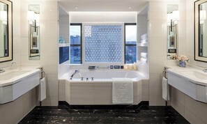 Um banheiro moderno com uma banheira grande, duas pias e uma janela com tela decorativa.