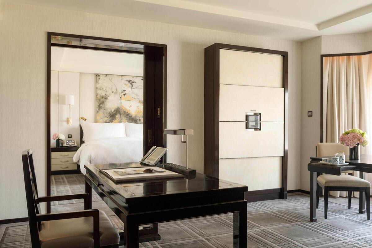 Una habitación de hotel con cama, mesita de noche, escritorio, silla y una obra de arte grande en la pared.