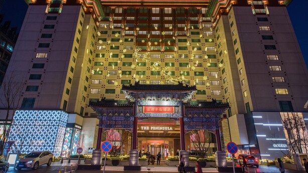 Un hotel de estilo arquitectónico tradicional, con una entrada destacada que presenta un arco decorativo e iluminación.