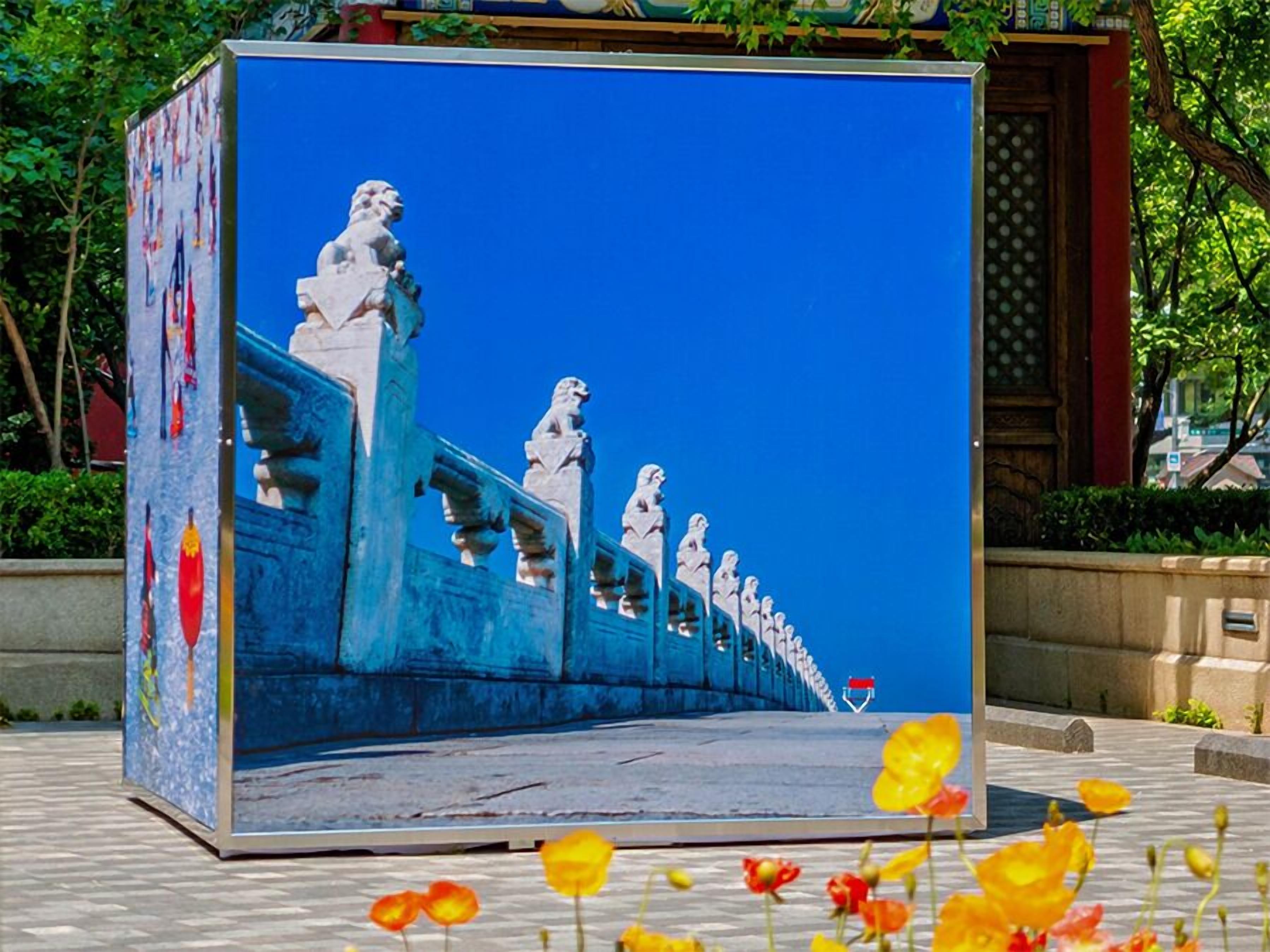 Una estructura grande y cuadrada, pintada de azul, con una serie de estatuas en la parte superior, sobre un cielo azul despejado.
