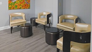 A room with three leather chairs, two black stools, and a colorful abstract painting on the wall. - Quality Inn Colchester - Burlington (Colchester)