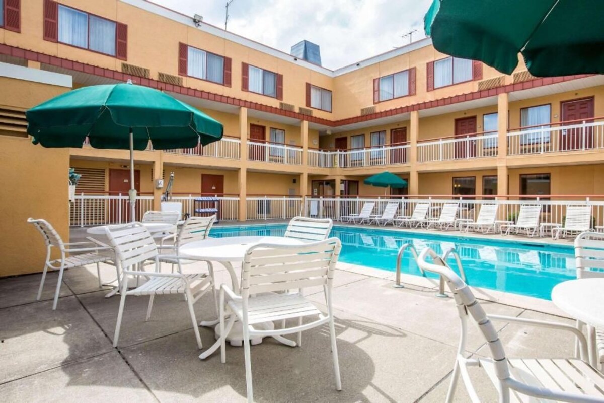 A hotel with a pool, outdoor seating, and umbrellas.