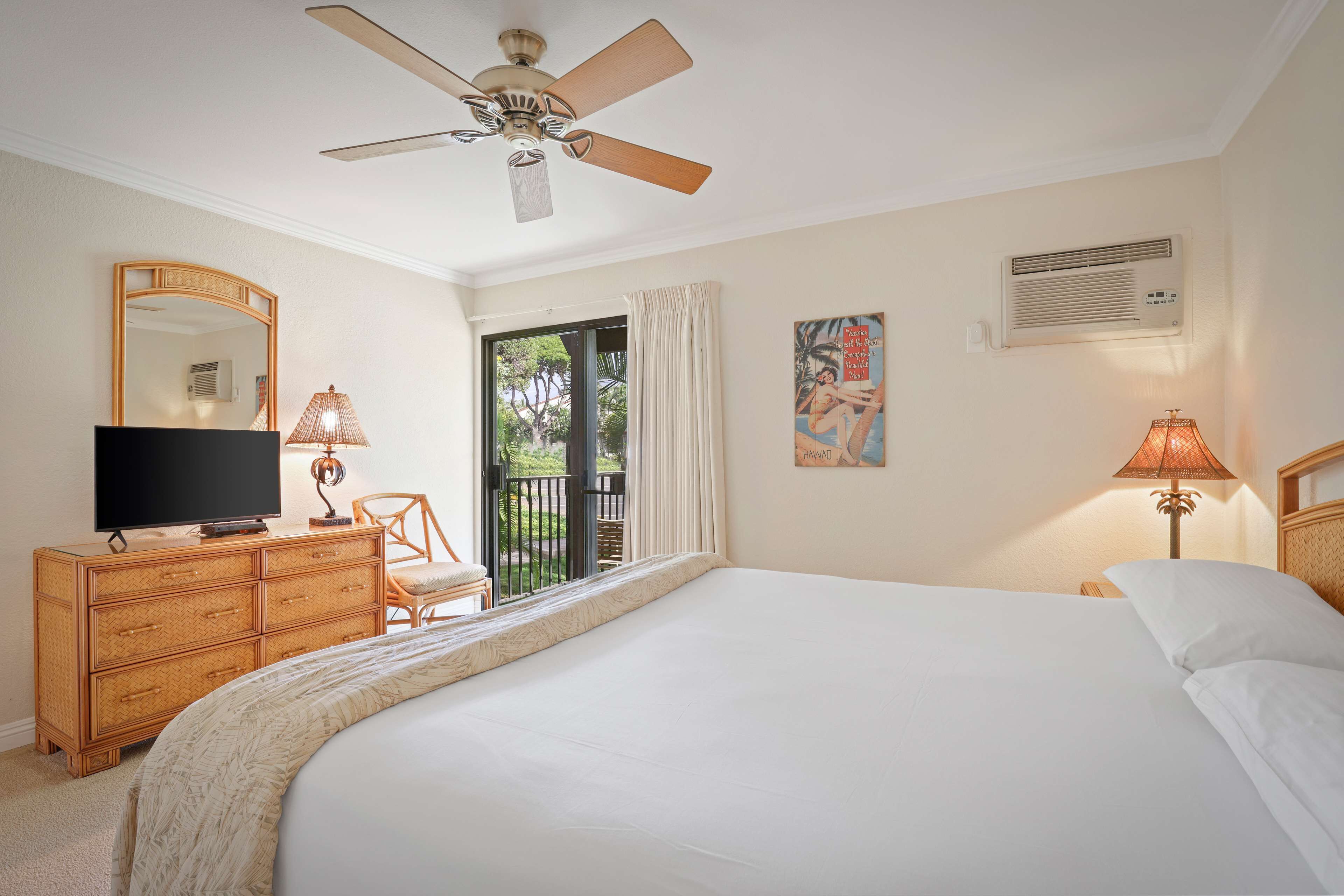 Une chambre d’hôtel équipée d’un lit, d’une télévision, d’une commode, d’une chaise, d’un ventilateur de plafond, d’une fenêtre avec des rideaux et d’un climatiseur fixé au mur.