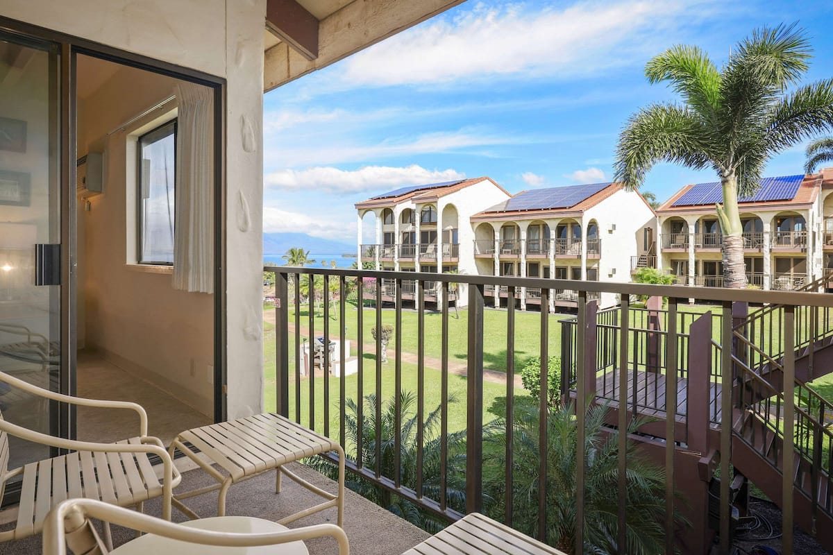 A balcony with a view of a resort with multiple buildings and palm trees.
