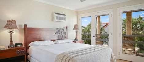 A hotel room with a bed, ceiling fan, two bedside lamps, a nightstand, and a view of the outdoors through a sliding glass door.