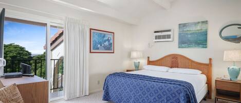 A bedroom with a bed, a desk, a chair, a ceiling fan, a window with curtains, and a balcony.