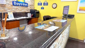 A reception area with a Days Inn sign, a clock, and a computer monitor. - Days Inn by Wyndham Mason City (Mason City)