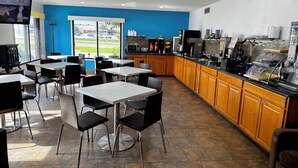 A modern cafe with tables and chairs, a coffee machine, and a view of the street. - Days Inn by Wyndham Mason City (Mason City)