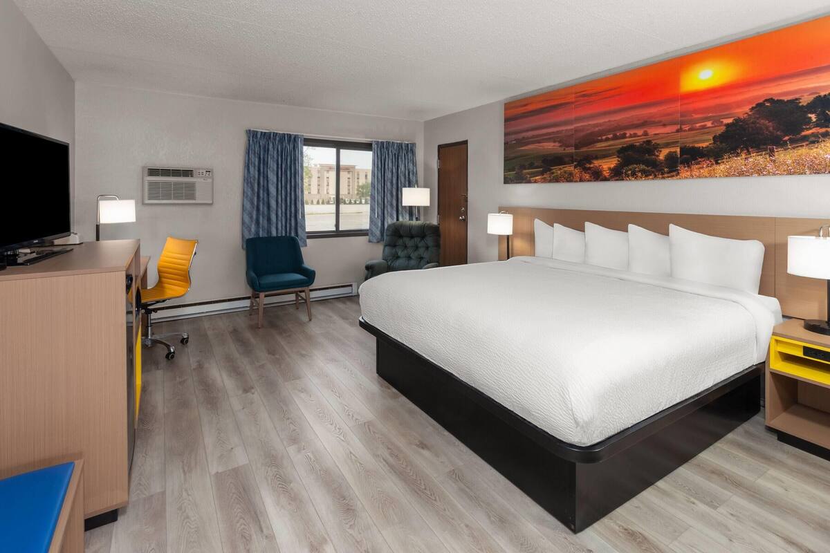 Une chambre d’hôtel avec un grand lit, un bureau avec un ordinateur, une chaise et un téléviseur.