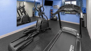 A gym with exercise equipment, a mirrored wall, a water dispenser, and a clock. - Days Inn by Wyndham Mason City (Mason City)