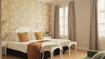 Un dormitorio con una cama grande, dos mesitas de noche, una lámpara auxiliar y un sillón verde, además de una araña.