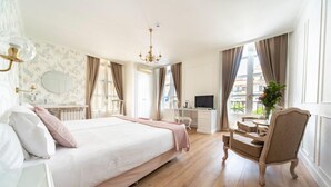 Un dormitorio amplio con una cama grande, un escritorio, una silla y un televisor.