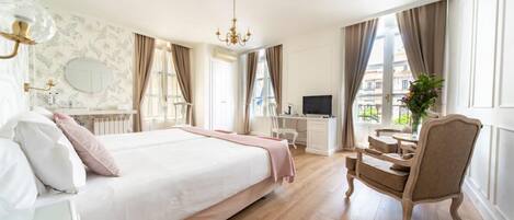 A spacious bedroom with a large bed, a desk, a chair, and a TV.