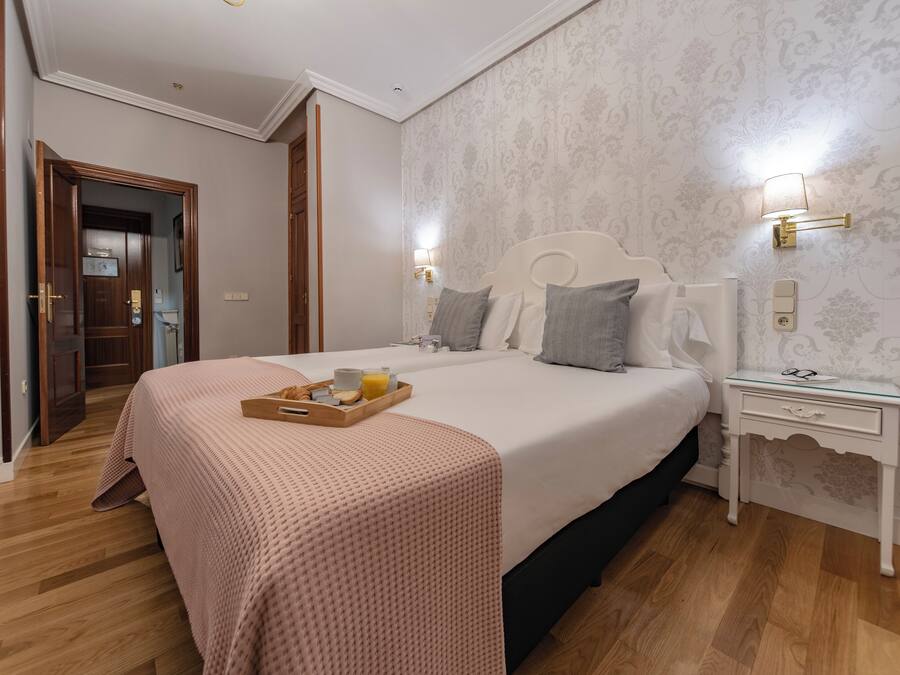 Quarto com cama grande, mesas de cabeceira e bandeja com itens de café da manhã.