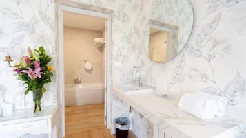 Un baño con tocador blanco, lavamanos, espejo y ducha.