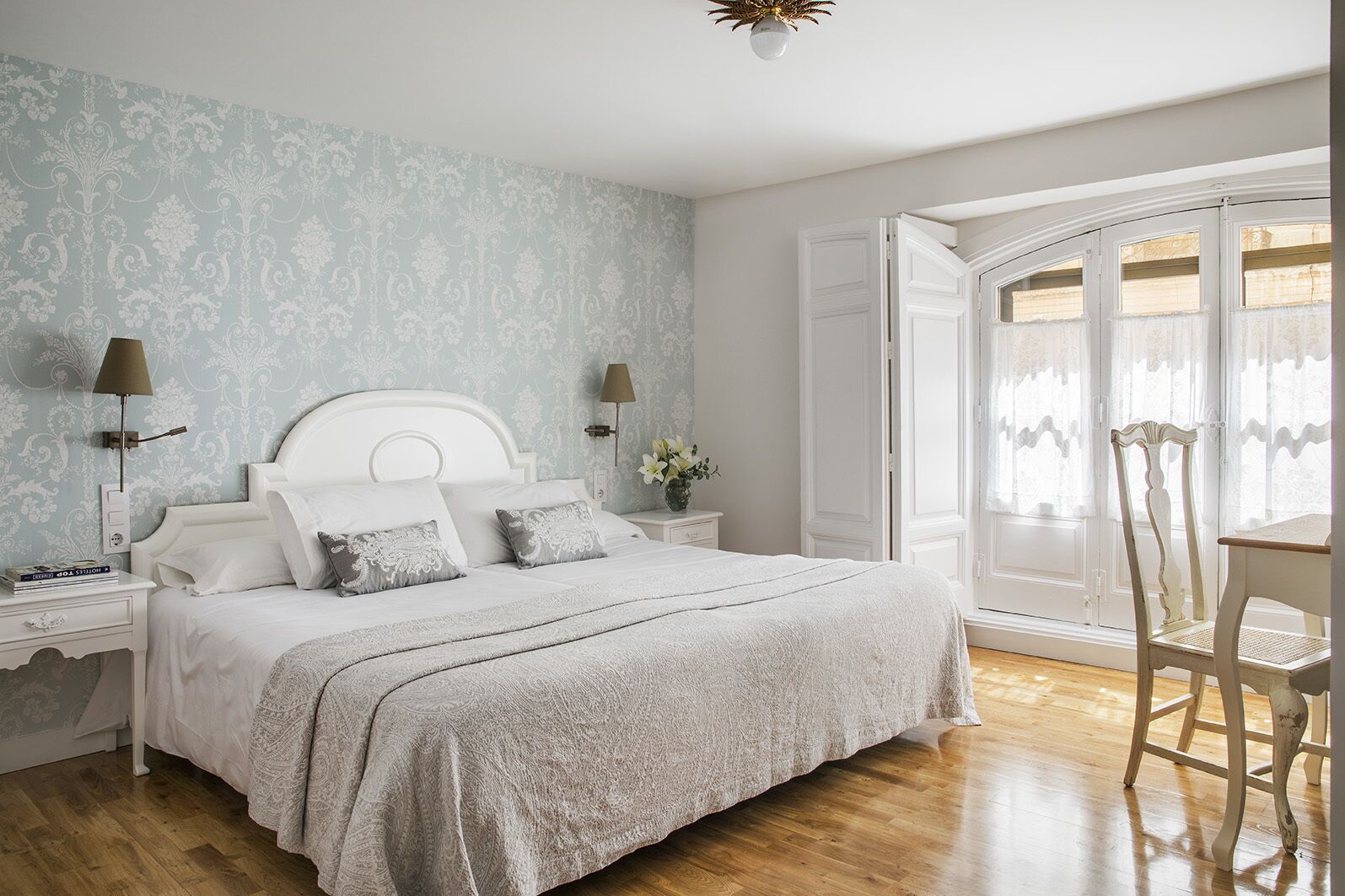 Una camera da letto con un letto grande, due comodini, una sedia e una finestra con tende.