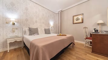 Un dormitorio ordenado con cama, mesitas de noche, un escritorio y una silla.