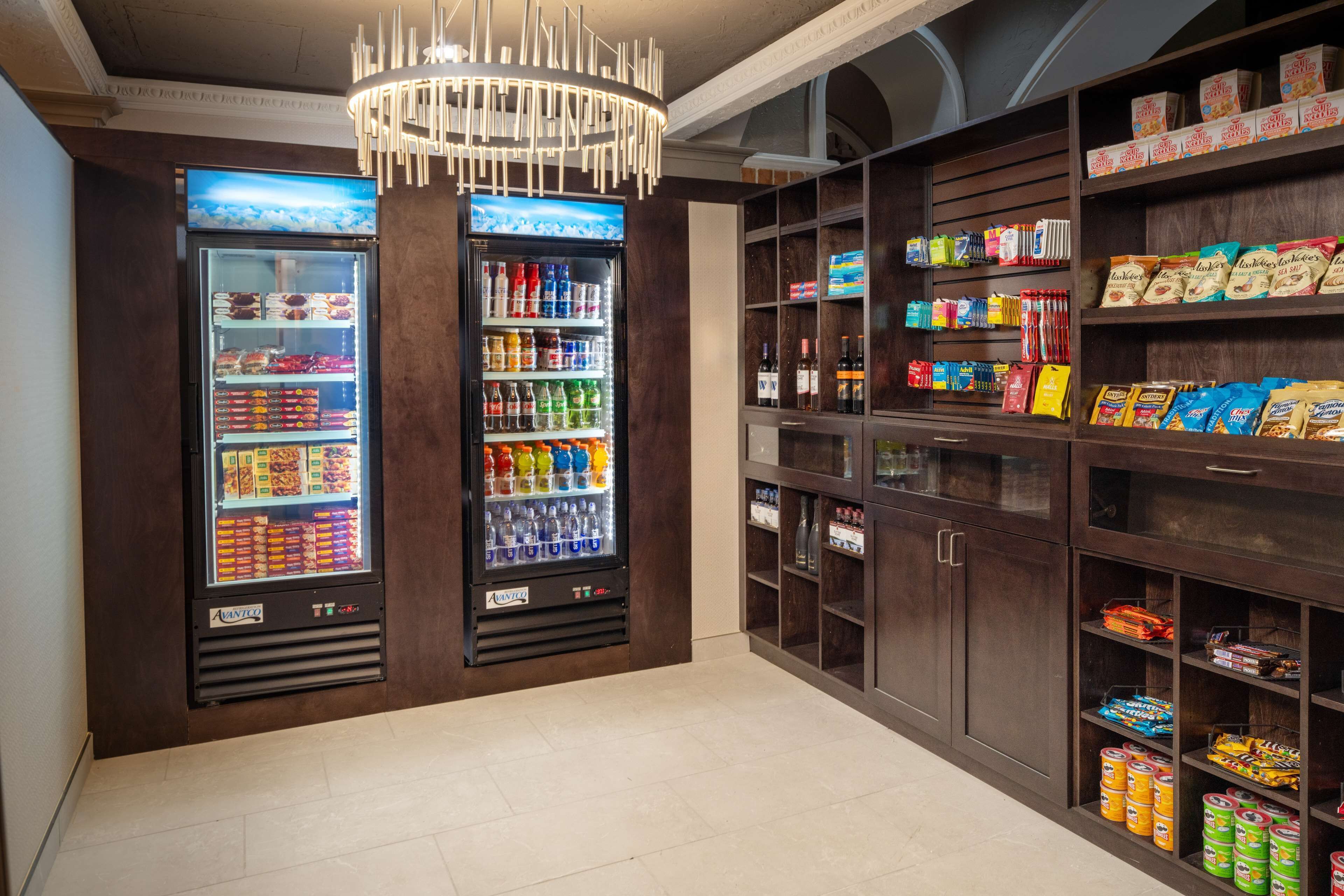 Eine gut beleuchtete Snackbar mit zwei Getränkeautomaten und Regalen voller Snacks und Erfrischungen.