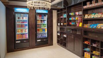 A well-lit snack bar with two beverage dispensers and shelves stocked with snacks and beverages.
