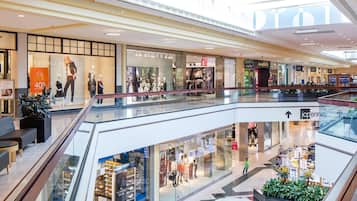 A shopping mall with multiple stores, including LOFT and GAP, and a glass railing with seating areas.