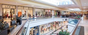 Un centro comercial con varias tiendas, incluyendo LOFT y GAP, y una barandilla de vidrio con zonas de descanso.