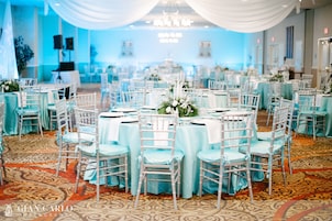 Un salón de banquetes con mesas redondas, sillas y suelo alfombrado.