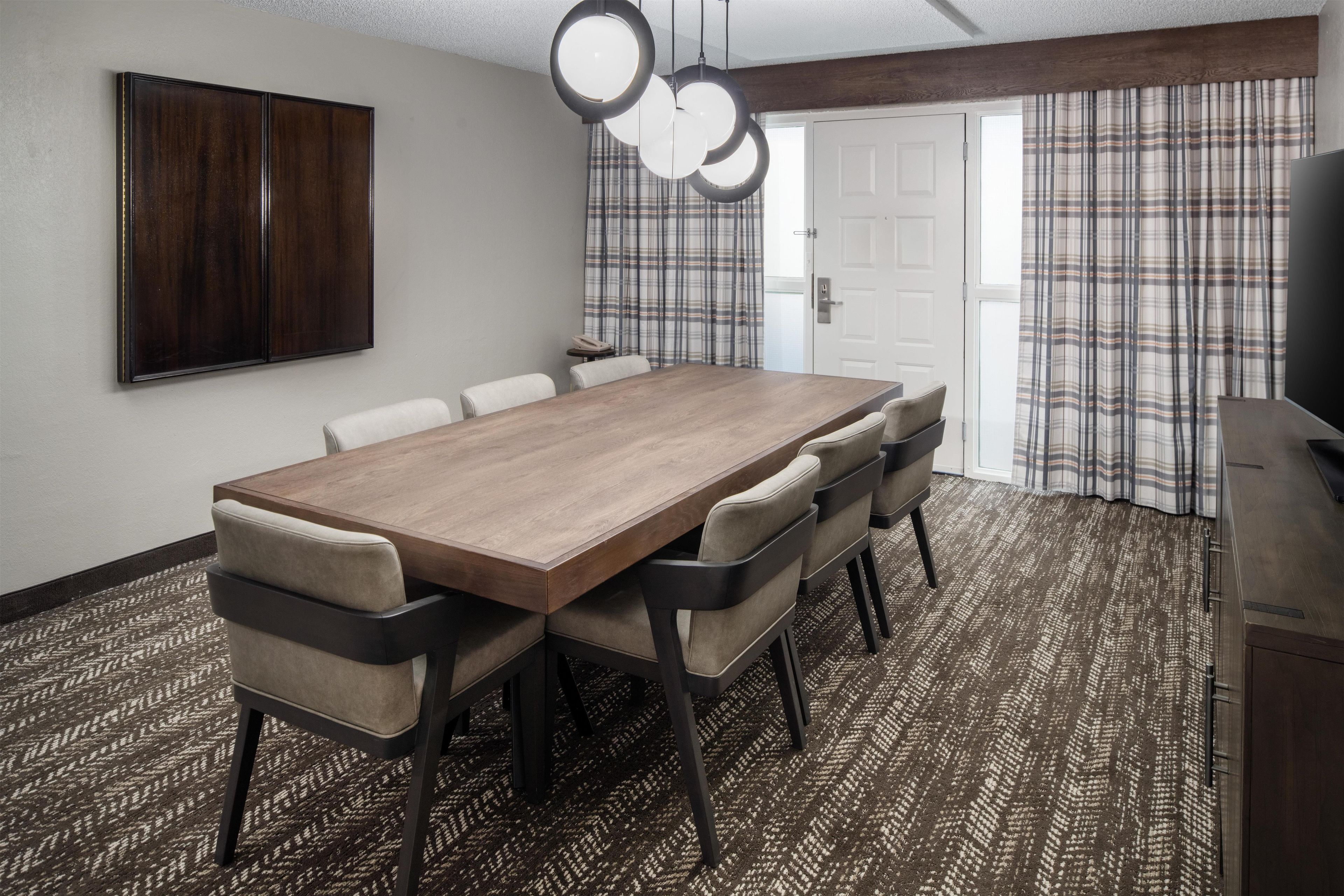A conference room with a wooden table, six chairs, a large mirror, and a patterned carpet.