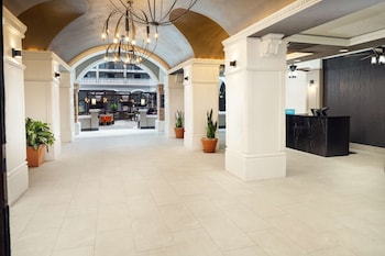 A spacious living room with a patterned rug, a beige sofa with multiple cushions, and several chairs. at Embassy Suites by Hilton Orlando North
