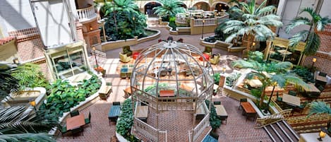 A hotel atrium with multiple floors, outdoor seating areas, and a central garden.