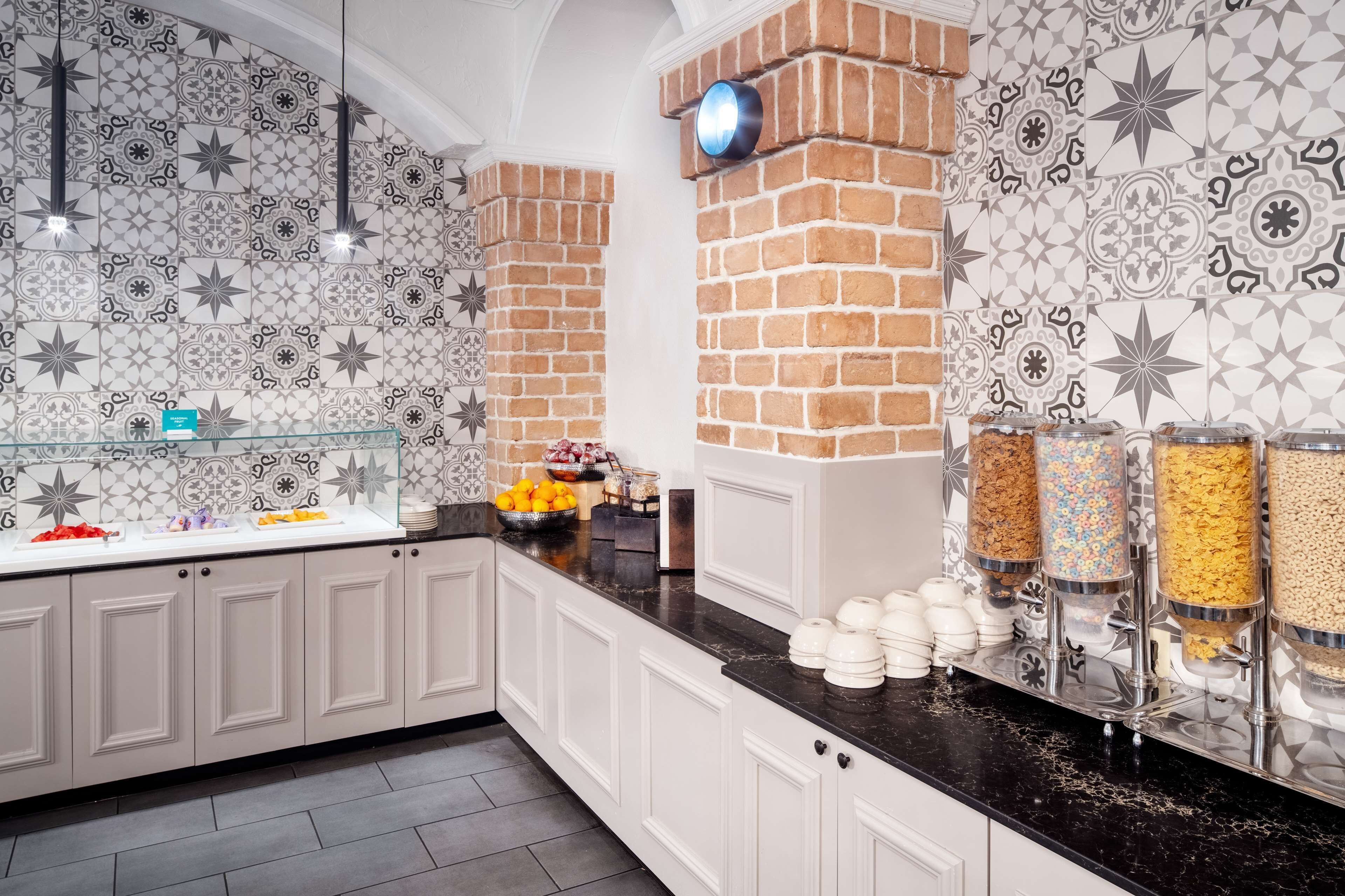 A kitchen with white cabinets, a black countertop, and a decorative backsplash with geometric patterns.
