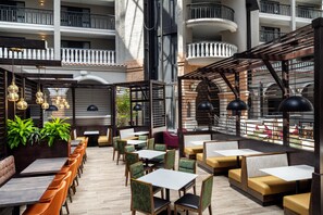 Un espacio interior amplio con diversas opciones de asientos, incluyendo mesas y bancos, y vista al exterior del edificio.
