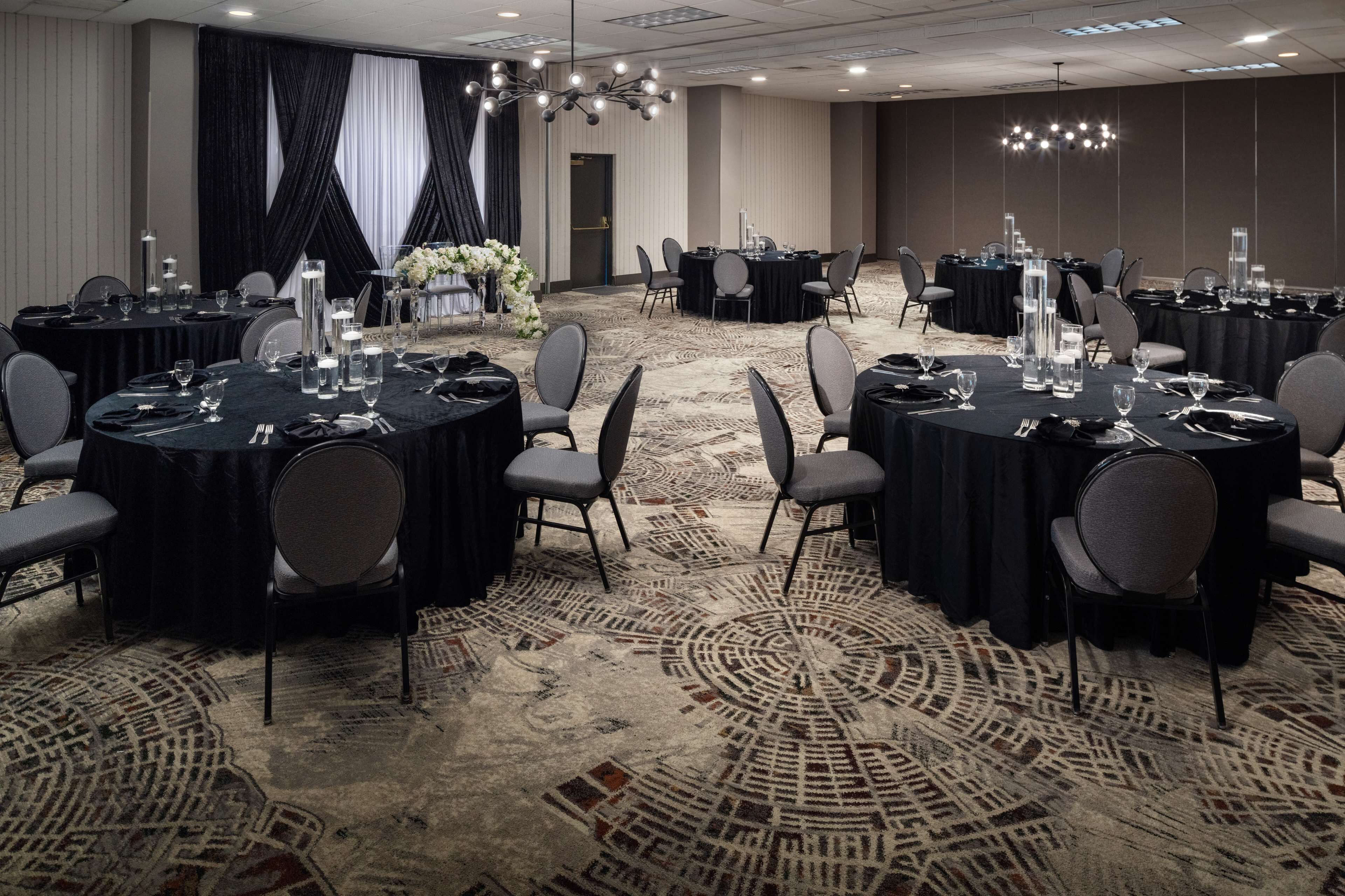 A conference room with round tables, chairs, and a carpeted floor.