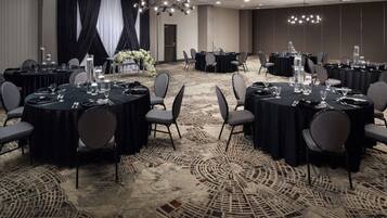 A conference room with round tables, chairs, and a carpeted floor.