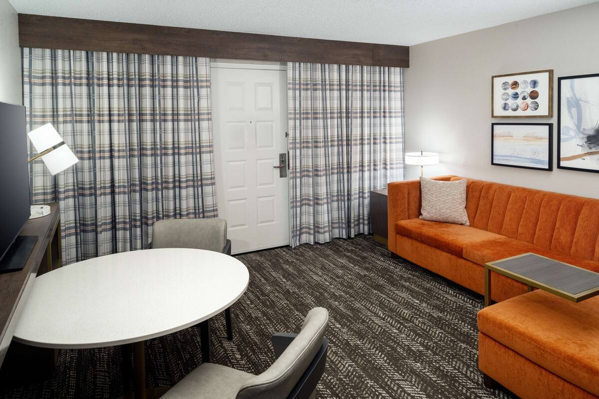 Een hotelkamer met een geruit gordijn, een bank, een tafel en een televisie.