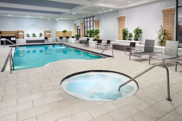 An indoor swimming pool with a hot tub, lounge chairs, and potted plants. - Embassy Suites by Hilton Orlando North (Altamonte Springs)