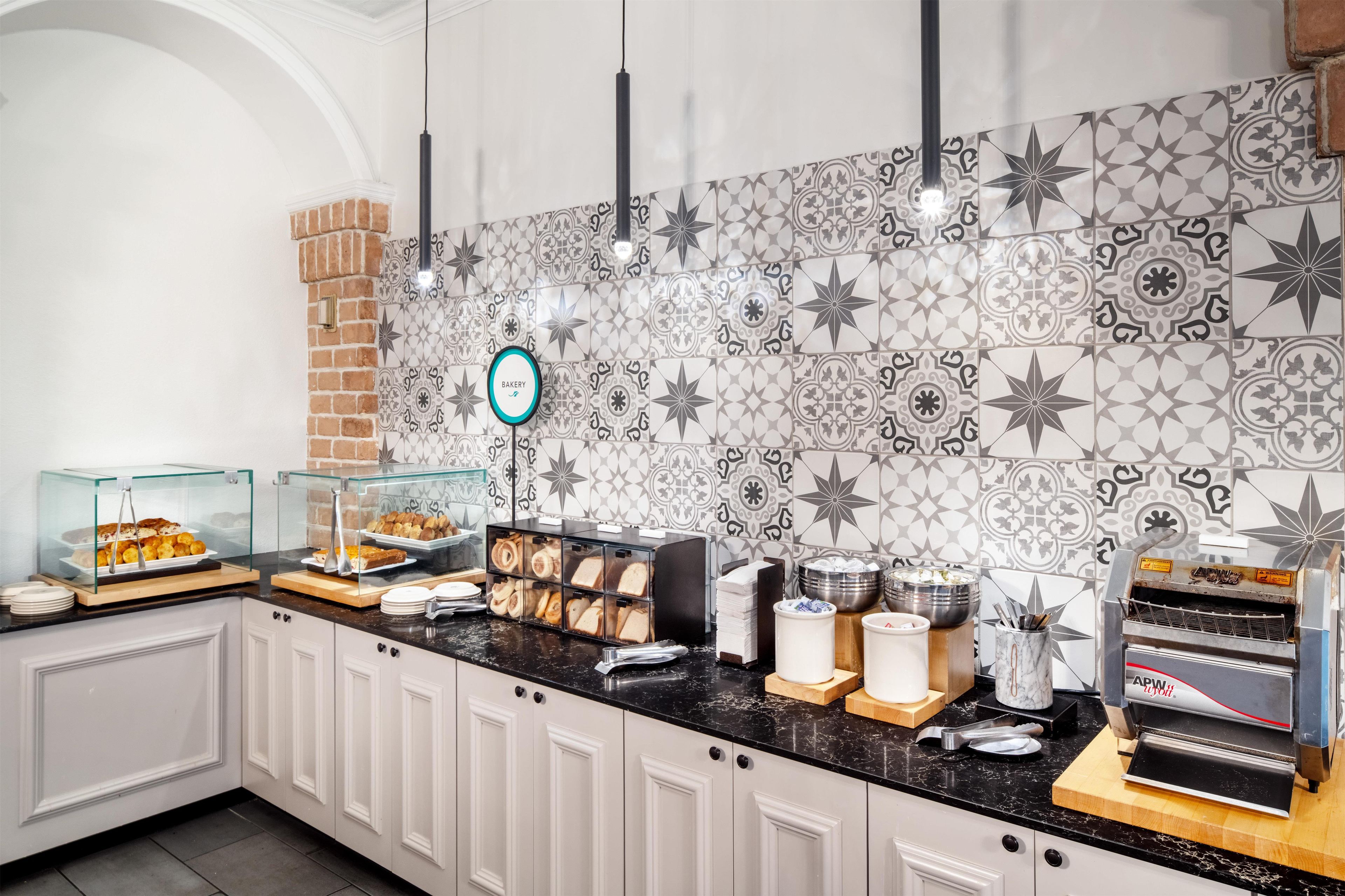 A breakfast buffet with various food items, a bakery sign, and a coffee machine.