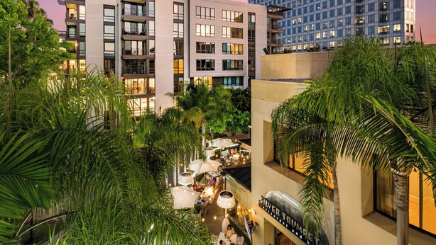 Un hotel de varios pisos, con zonas de estar al aire libre y abundante vegetación.