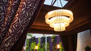 Un interior moderno con una gran lámpara circular, paredes con jardín vertical y cortina estampada.