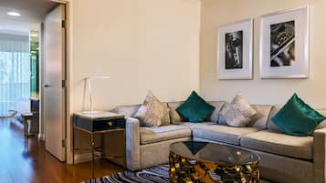 A modern living room with a sofa, a coffee table, and a side table. There are two framed pictures on the wall.